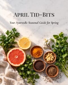 A bright, clean flat lay of April's seasonal ingredients — halved lemon and grapefruit, fresh green herb sprigs (parsley, coriander, or watercress), small clay dishes of warming spices (turmeric, ginger, mustard seed, cumin), and perhaps a single spring blossom — on a white marble or natural linen surface. Soft, even natural daylight with a gentle warmth. Text overlay reads "April Tid-Bits. Your ayurvedic seasonal guide for spring".